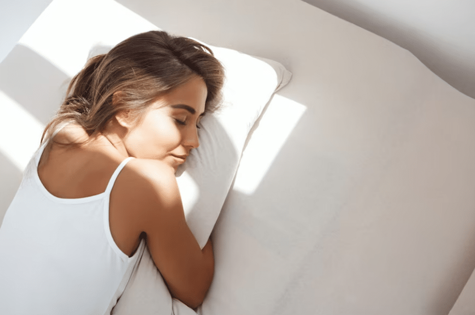 Woman-lying-on-her-stomach-hugging-pillow-in-bed